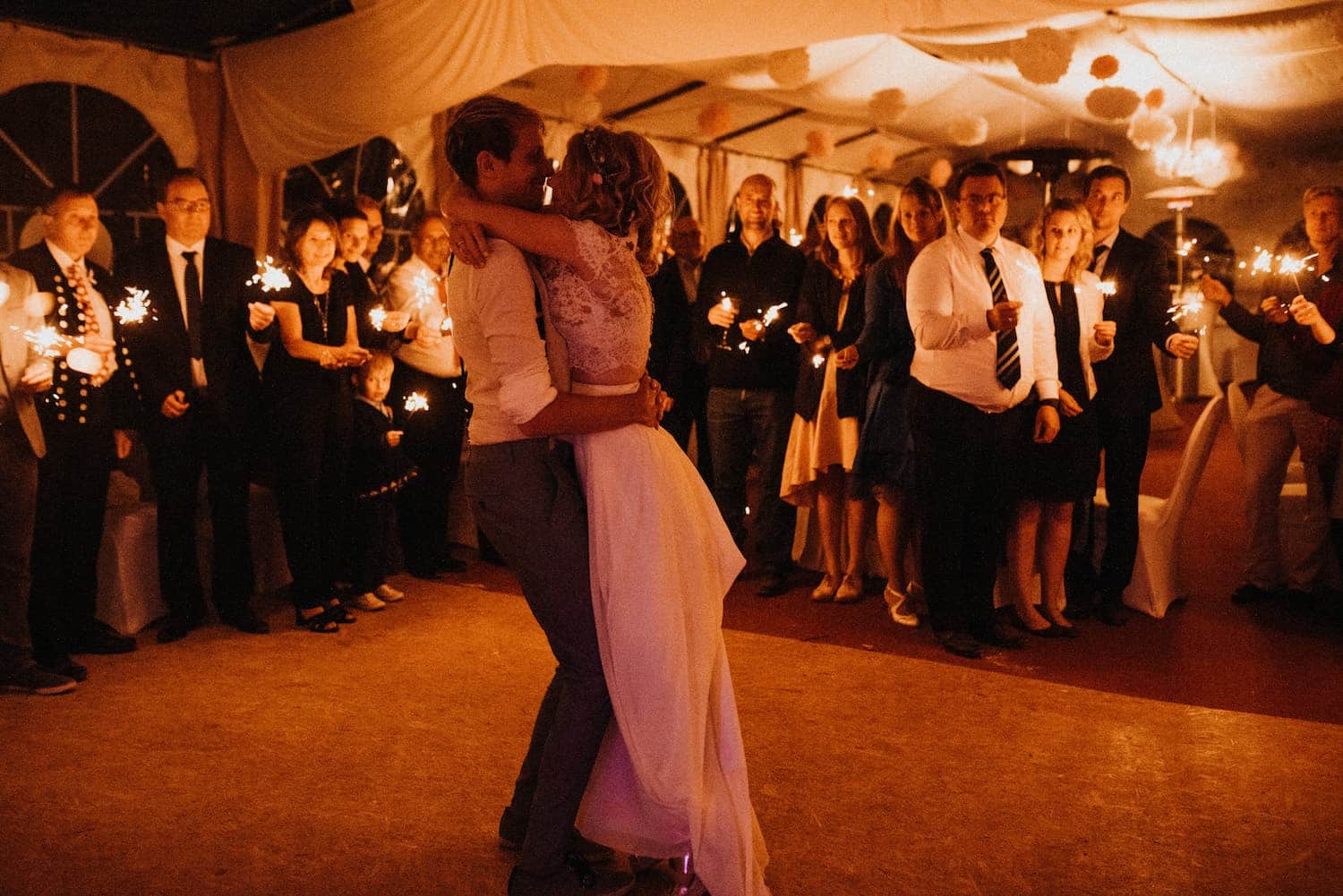 Das Hochzeitspaar umarmt sich beim Hochzeitstanz und wird von den Gästen gefeiert im Restaurant Müggenbusch in Lübeck.
