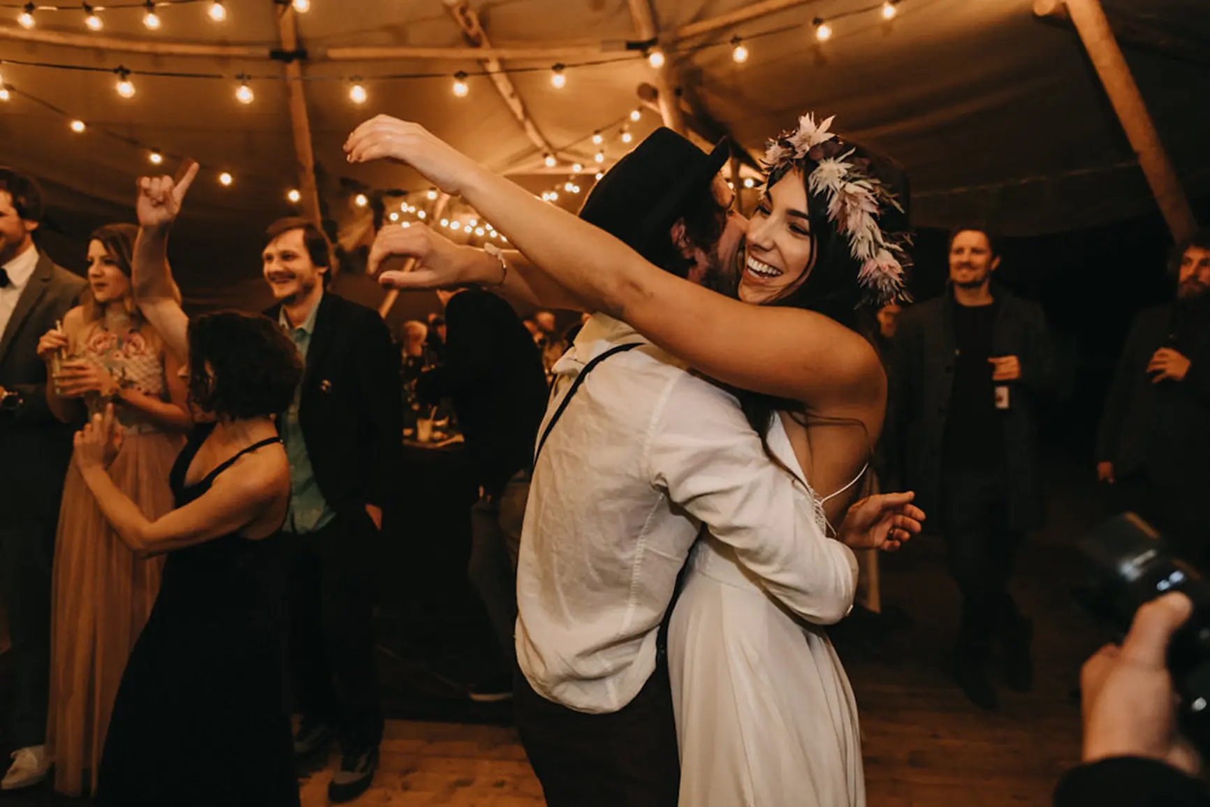 Hochzeitspaar umarmt sich beim Hochzeitstanz und feiert ausgelassen auf einer wunderschönen Hochzeitsparty mit vielen Gästen und Live-Musik.