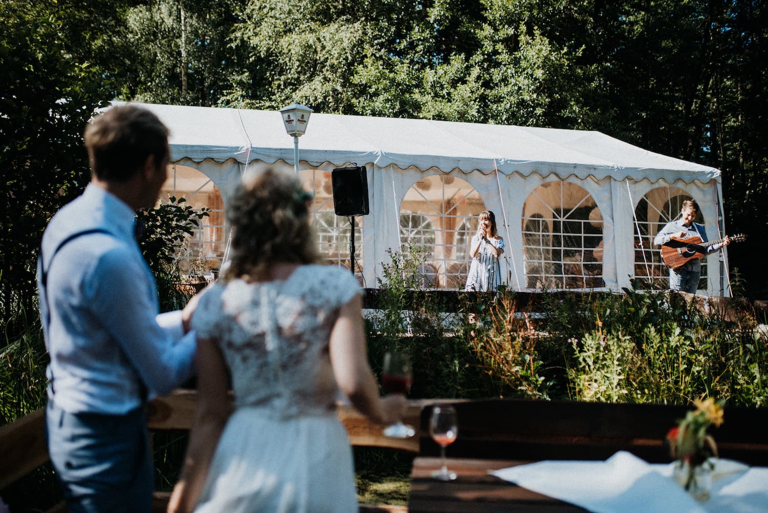 Das Brautpaar lauscht dem Gesang der Hochzeitssängerin auf ihrer Hochzeit im Restaurant Müggenbusch in Lübeck.