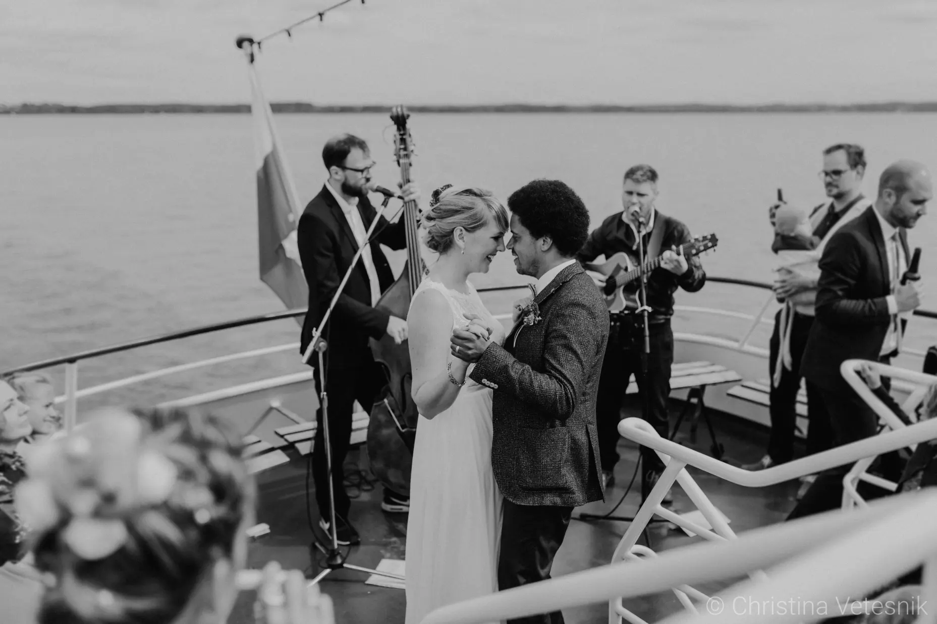 Ein Hochzeitspaar tanzt ihren Hochzeitstanz vor einer Live-Band, direkt an einem See.