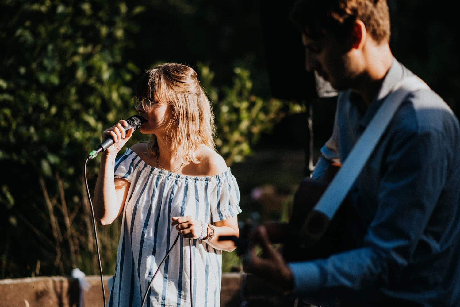 Hochzeitssängerin und Gitarrist musizieren im Restaurant Müggenbusch in Lübeck bei schönem Wetter im Freien.