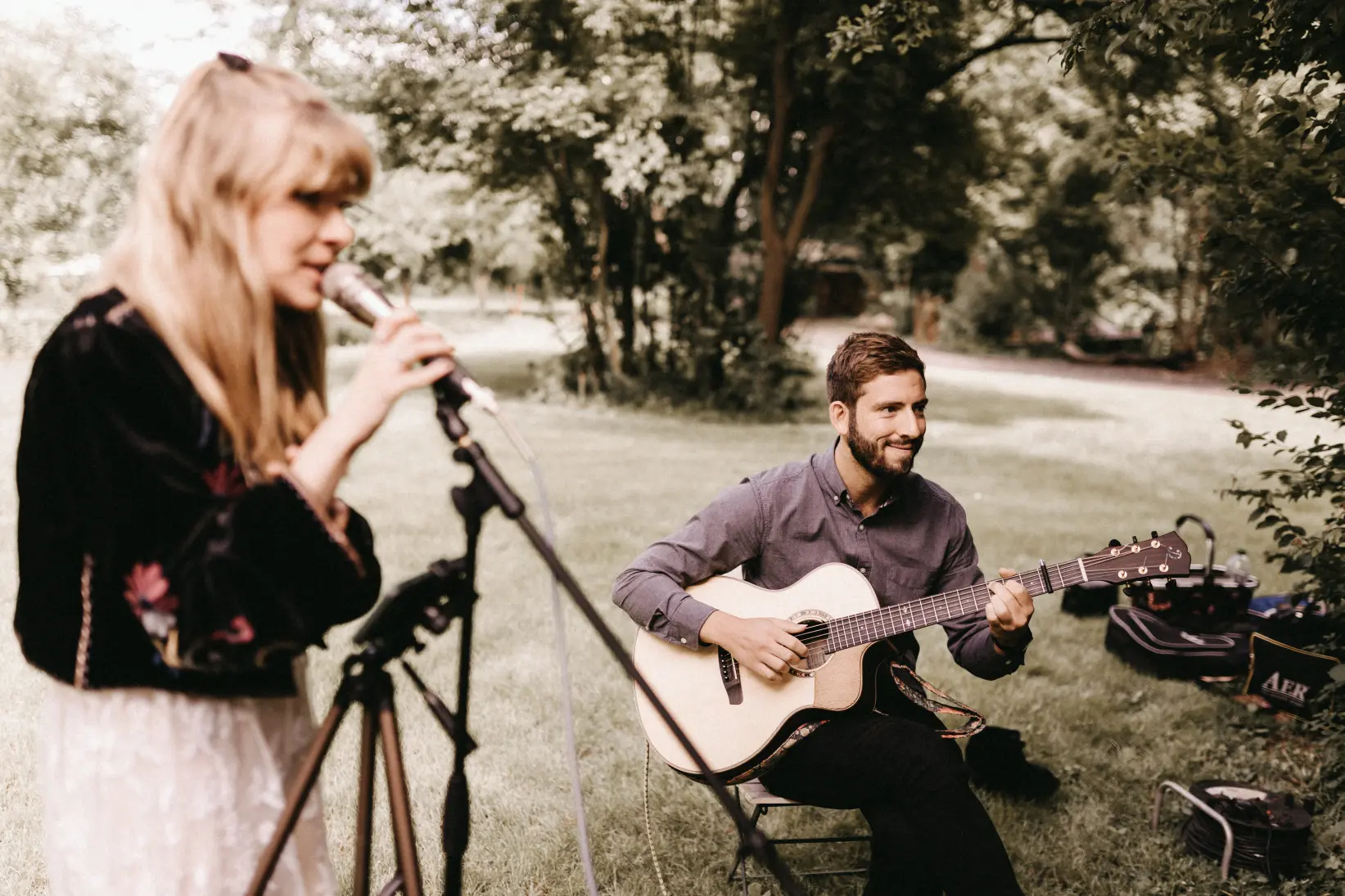 Hochzeitssängerin singt auf Sektempfang und wird von Gitarristen begleitet.